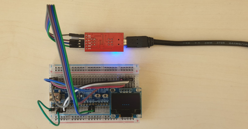 A photo of a breadboard with a maple mini clone STM32 processor board connected to an SDD1306 OLED display and a USB-serial adapter