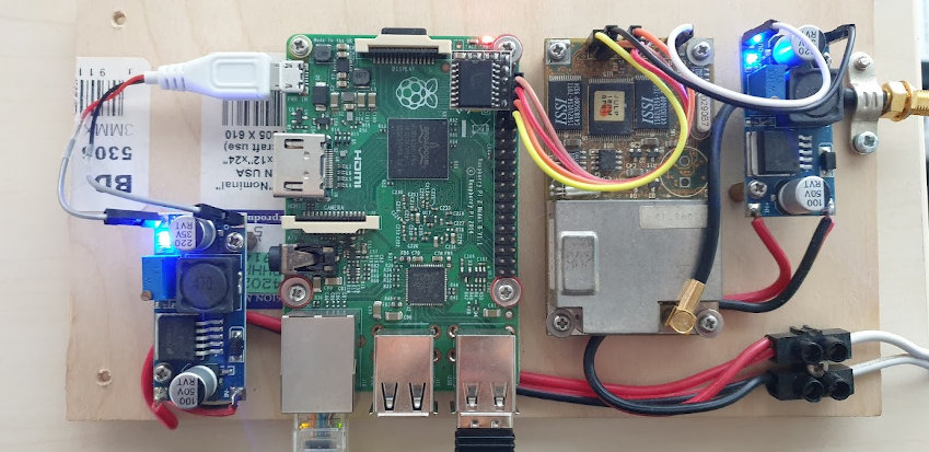 Photograph of Rockwell Jupiter GPS module connected to a Raspberry Pi with two buck convertor power supply modules mounted on a piece of plywood